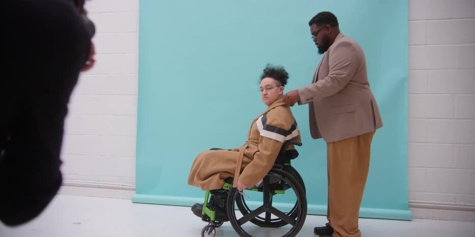 A black man poses a model in a wheelchair for a photograph