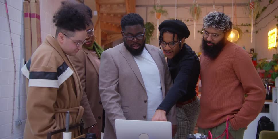 Group of friends standing looking at laptop concentrated and talking to each other
