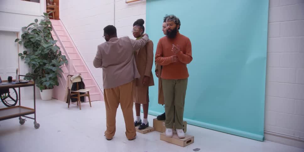 Man adjusting three models in a studio and preparing for a photo shoot