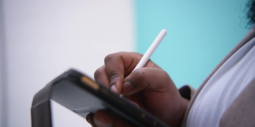 A black man writes on a tablet and speaks