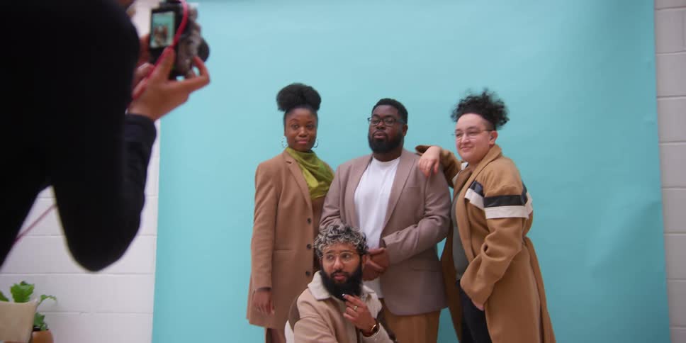 A group of people wearing brown jackets poses for the camera in the studio