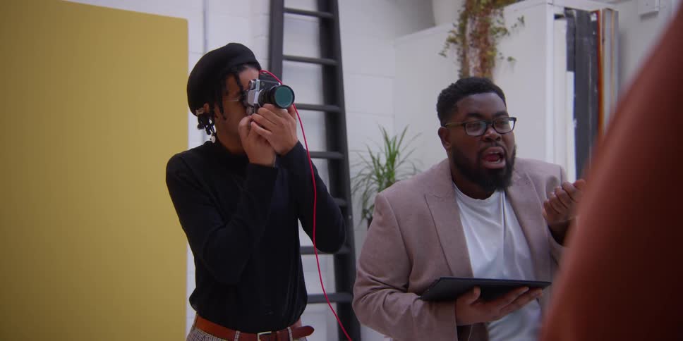 A man holding a tablet stands next to a photographer