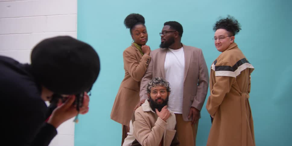 A group of models standing against a light blue wall for a photographer