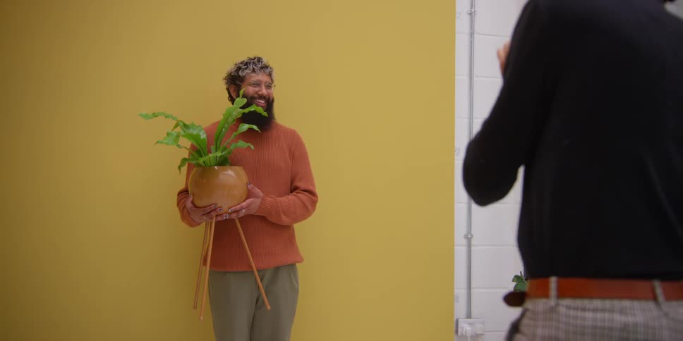 A man poses for a photograph with a plant