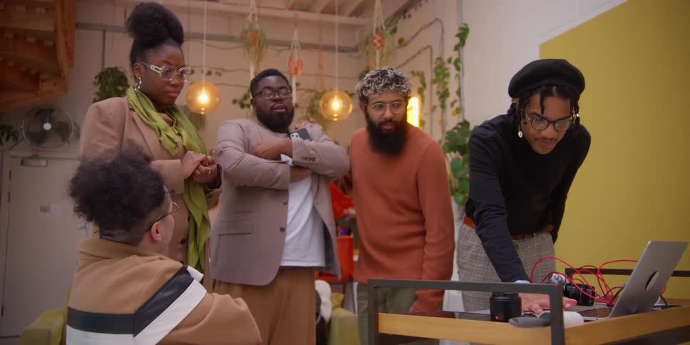People stand by a laptop and talk
