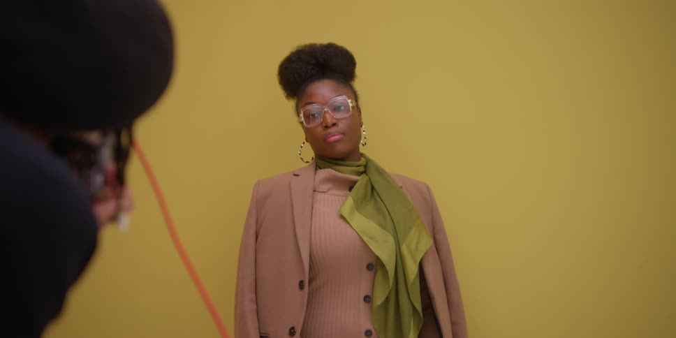 A model being photographed against a yellow background by a professional photographer