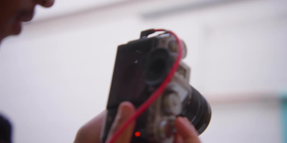 Closeup on a professional camera photographing three models in a studio