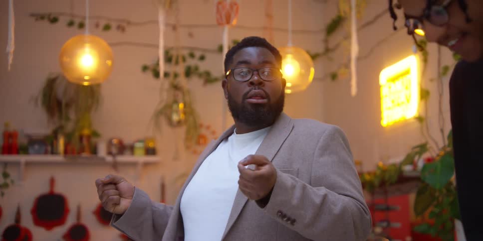 A black man speaks animatedly in a room