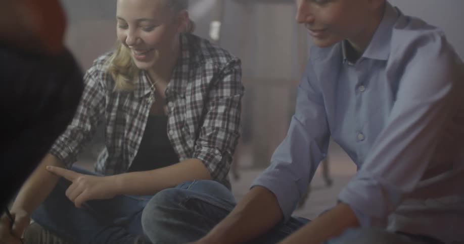 Two women in button down shirts laugh and talk in a warehouse