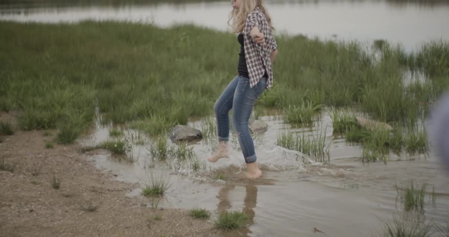 A woman splashes on a lake bank