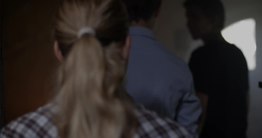 A boy is looking back over his shoulder as he and others walk through a corridor