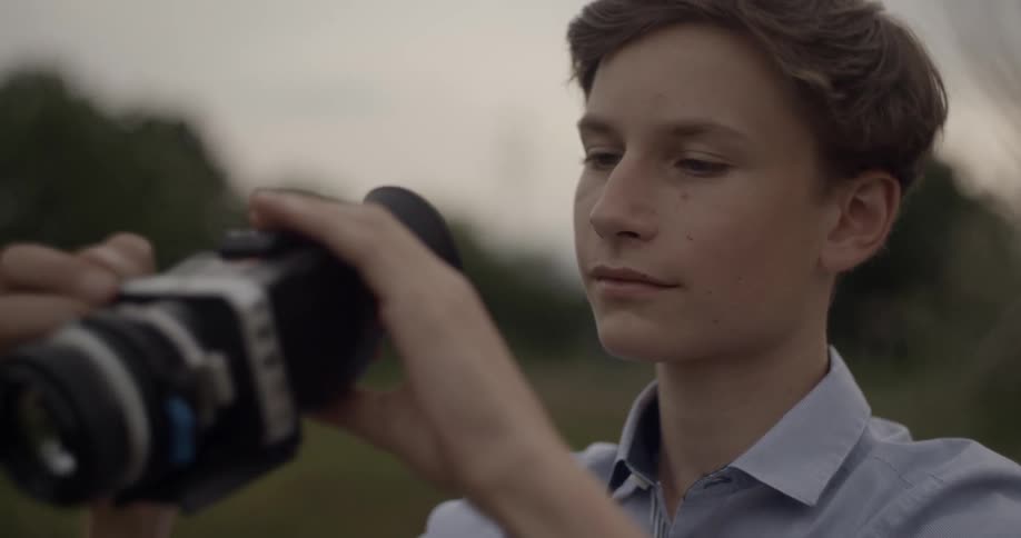 A teenage boy is using an eyepiece on a camera
