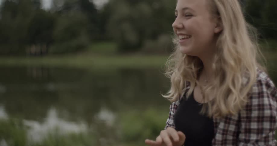 A girl is smiling near a lake