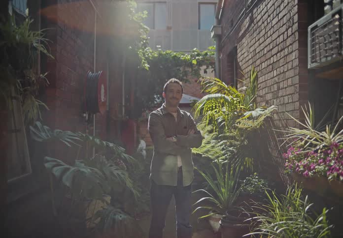 Man with arms crossed smiling in the middle of a corridor between houses