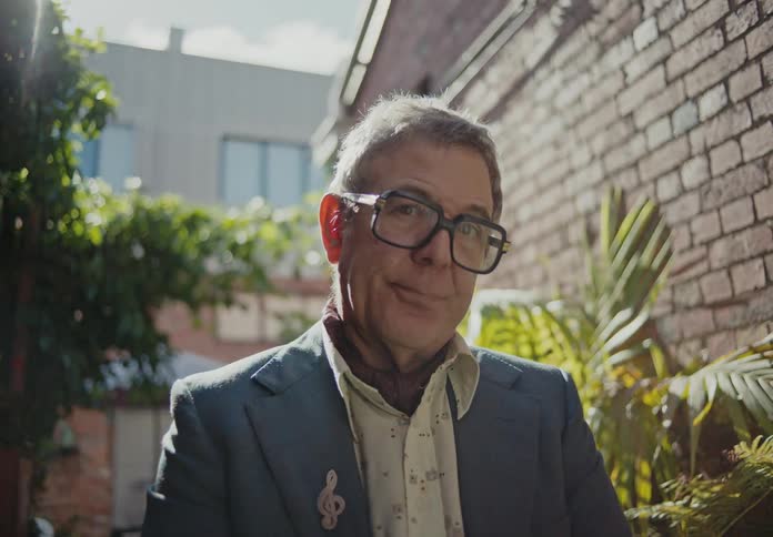 A man standing in formal clothes and glasses looking forward