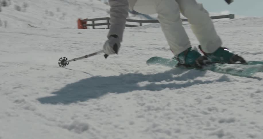Closeup of a snowcovered ground with a skier making a turn