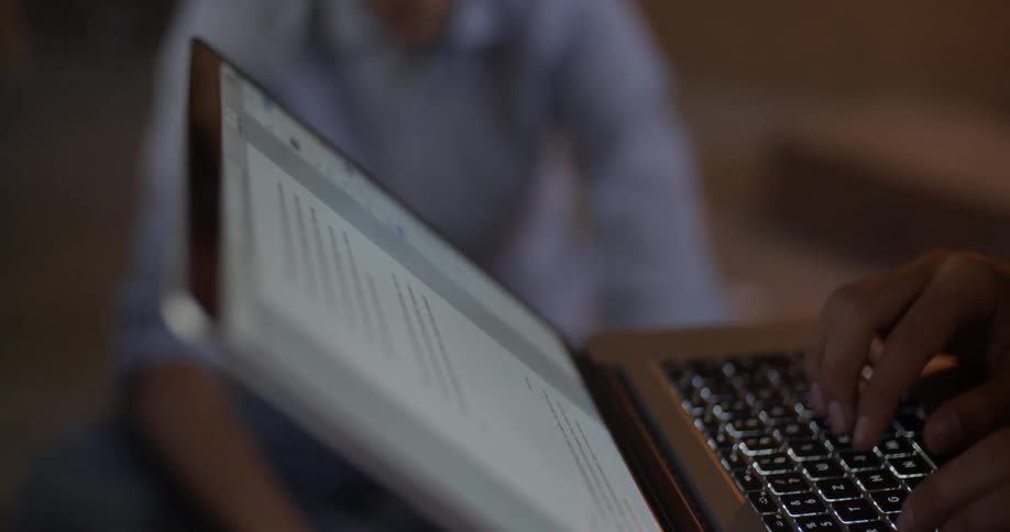 A person is using a laptop while another sits nearby