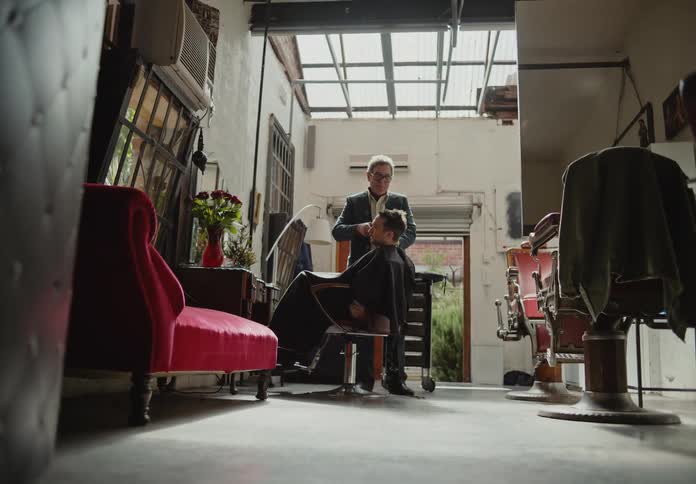 A haircut session in a welllit barber shop with a rustic aesthetic and a red vintage sofa