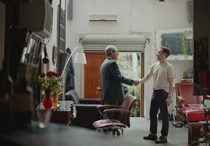 Barber talking to a customer and holding hands in farewell