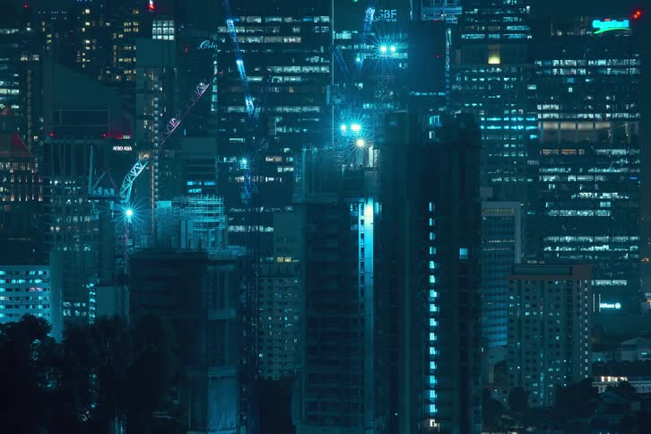 Some buildings in timelapse and being constructed by cranes and the lights of all the buildings are flashing quickly