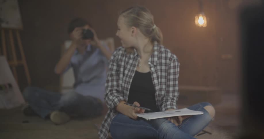 Boy taking a photograph of girl sitting near him