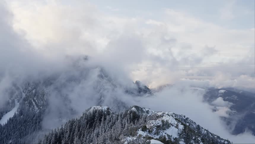 Panorama of mountain range covered by snow and clouds passing by