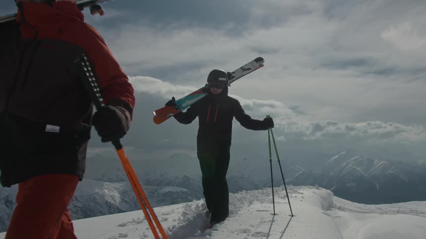 Two skiers walking along the top of a snow covered ridge