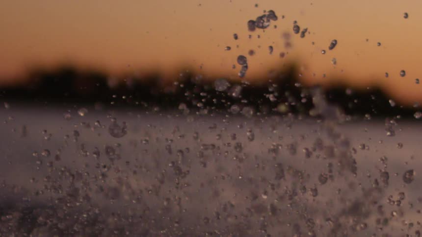 Extreme close up of water cuticles flying over a river in slow motion