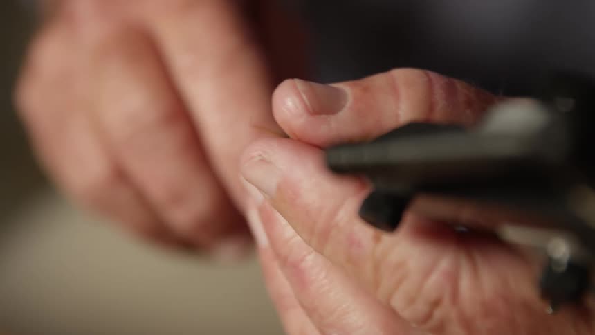 Extreme closeup of a mans hand tying a fishing line to a feather