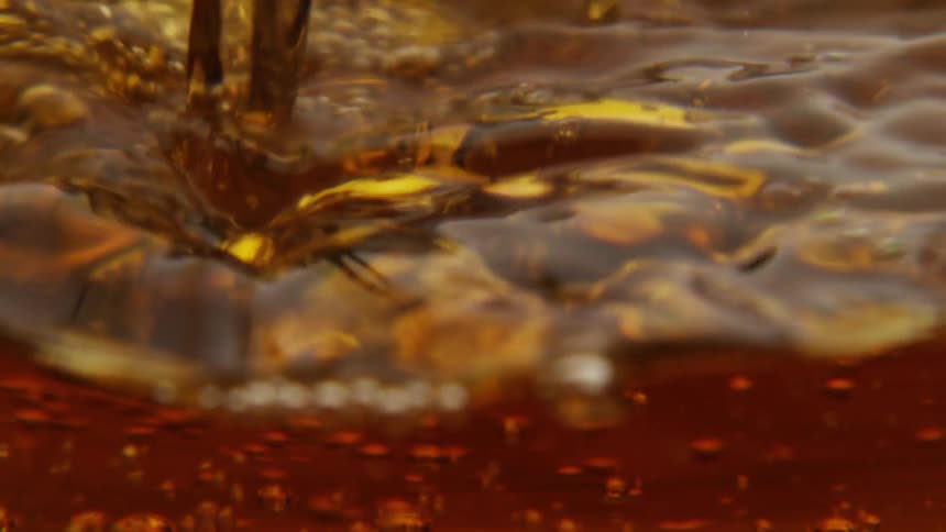 Extreme close up of orange colored liquid being poured