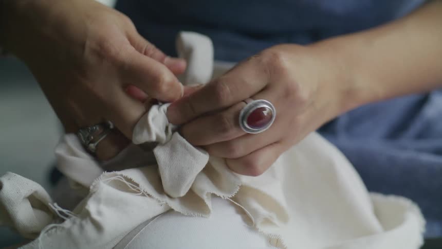 A person with some rings on their fingers tying a bag using a small rope