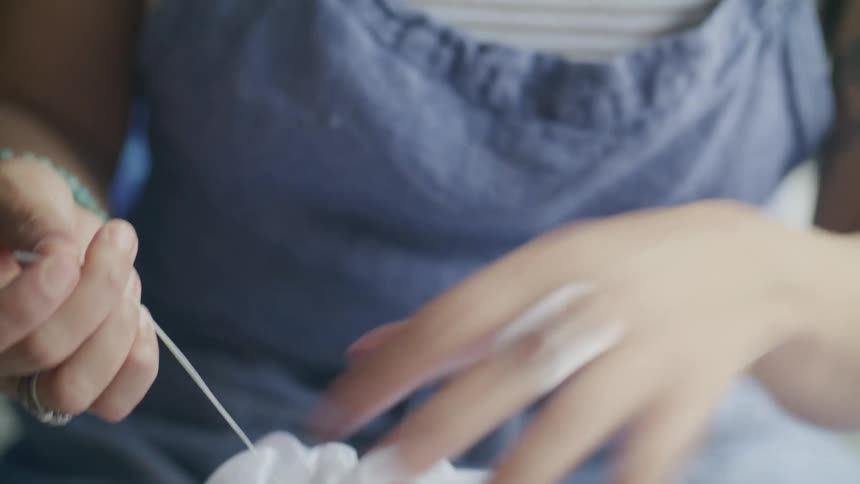 A young woman stiches a piece of fabric