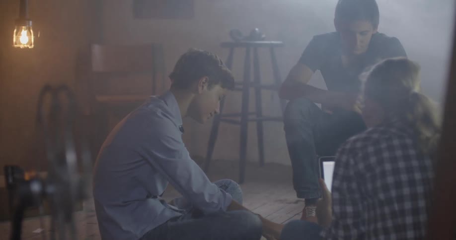 A group of teenagers are sitting in a room working on a project together