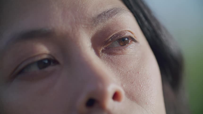 A person staring at some place and blinking his eyes while his facial skin is illuminated by sunlight