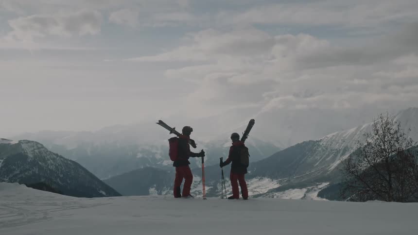 Two people with ski equipment standing in the middle of a snowy mountain