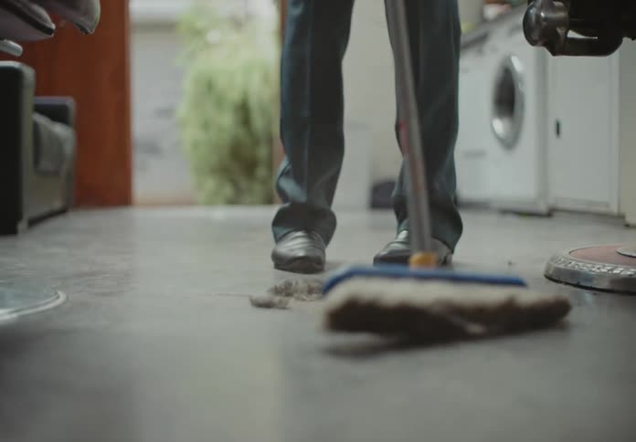 A man in a barbershop sweeps the floor