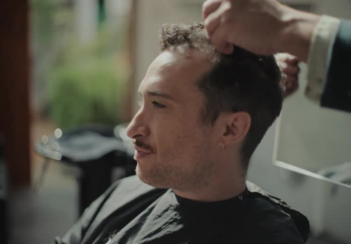A barber finishes up a haircut for his client