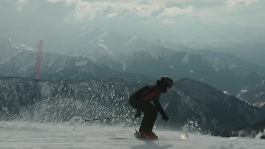 A person snow skis down a mountain on a partly cloudy day