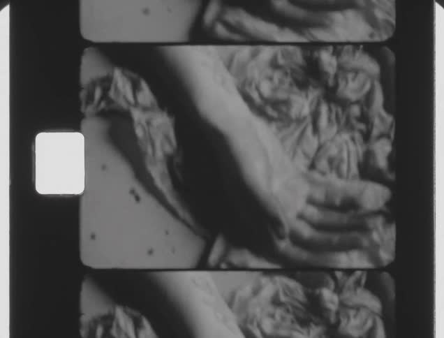 A person stretches their hands over a rumpled blanket