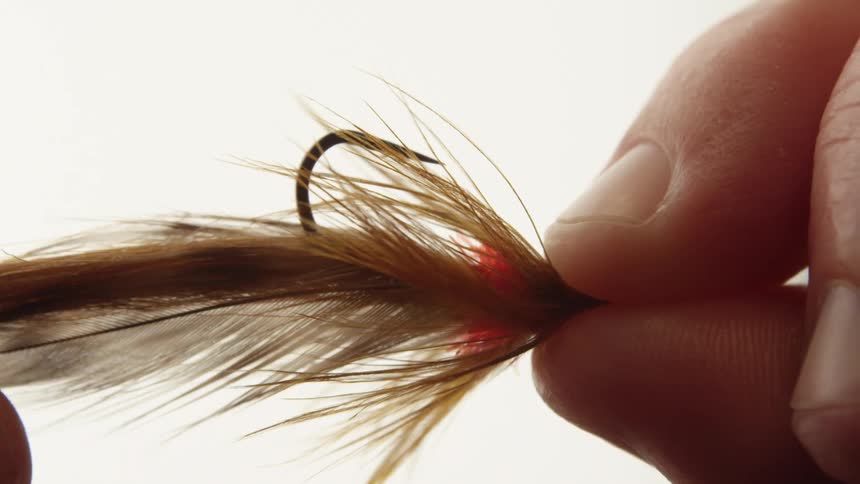 Extreme close on a persons fingers holding and running a hand under a hair