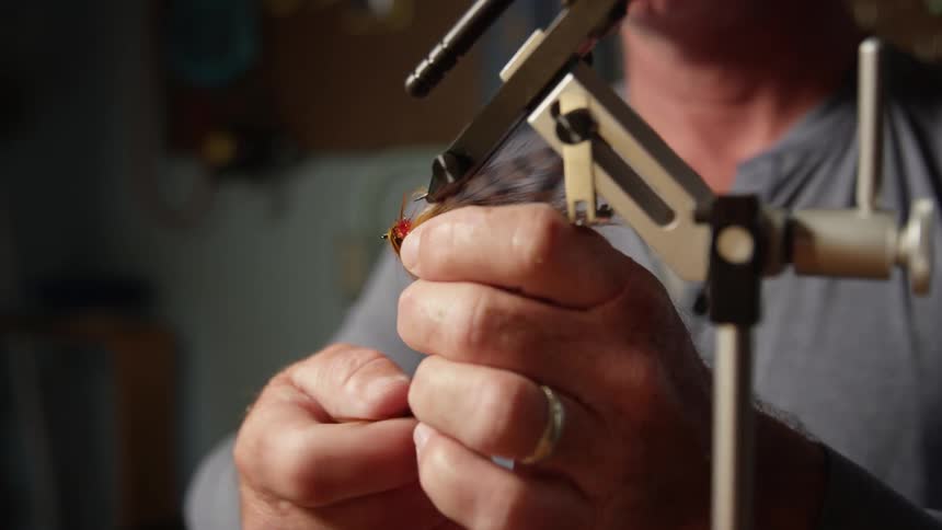 A person passing a feather on a line that is being held by a support