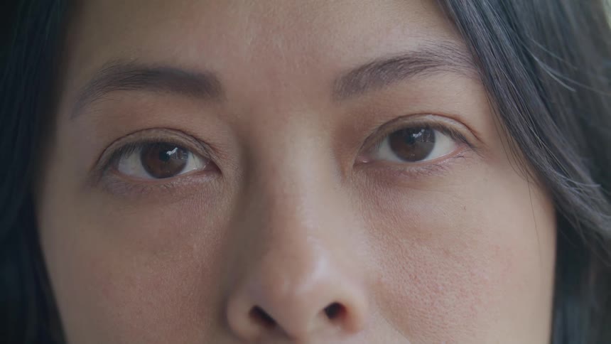 Extreme closeup on the face of a young woman opening her eyes