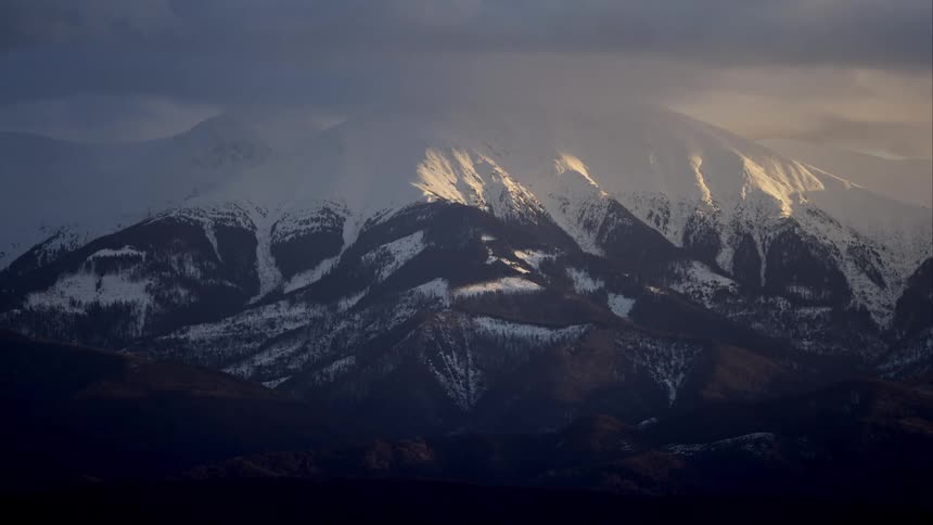 A huge rocky mountain with its top covered in snow
