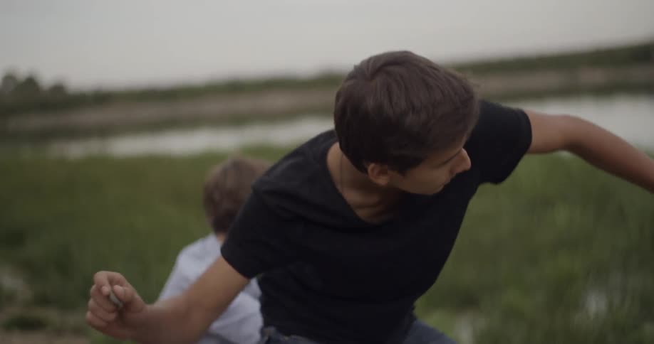 A man skips a rock near a person taking pictures