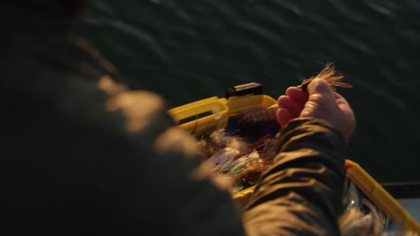 A fisherman opens a box to select a fly