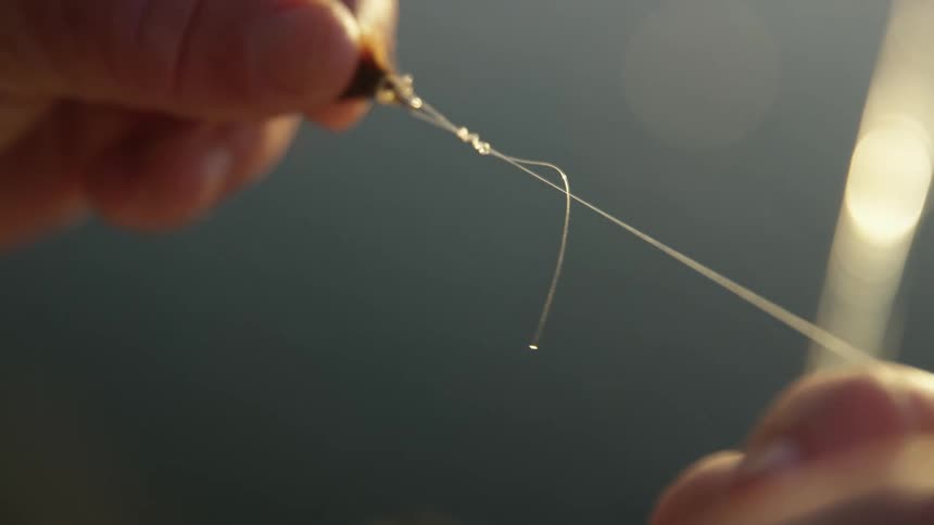 Close on the hand of a man holding a fishing line with a knot