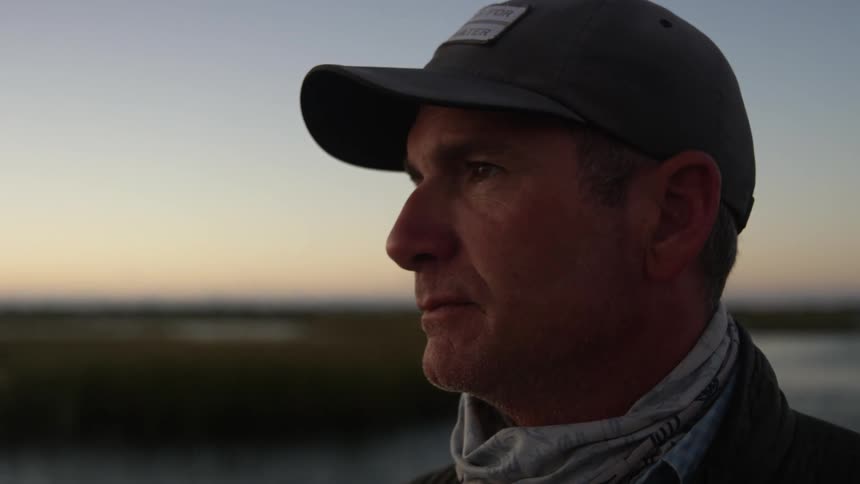Portrait of a man removing a cloth from his face while on a boat in the middle of a river a sunrise