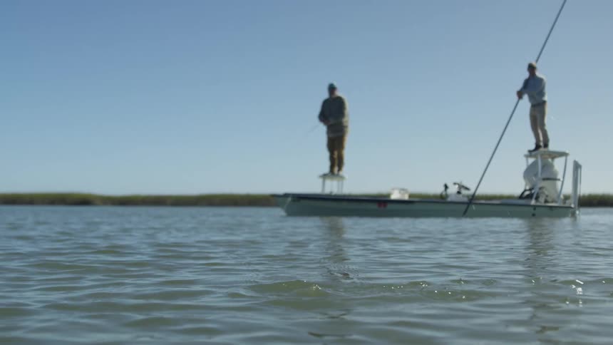 Two men standing on platforms on a narrow boat fish