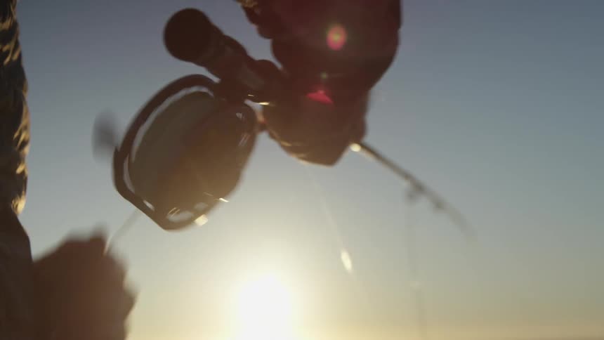 Closeup of a mans arm collecting line from a fishing rod