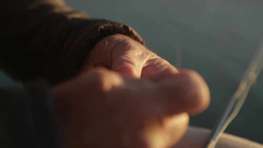 Hands with wrinkles grasping a delicate thread under warm light